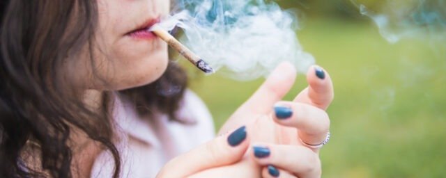 Girl smoking medical marijuana joint outdoors, close-up. Cannabi